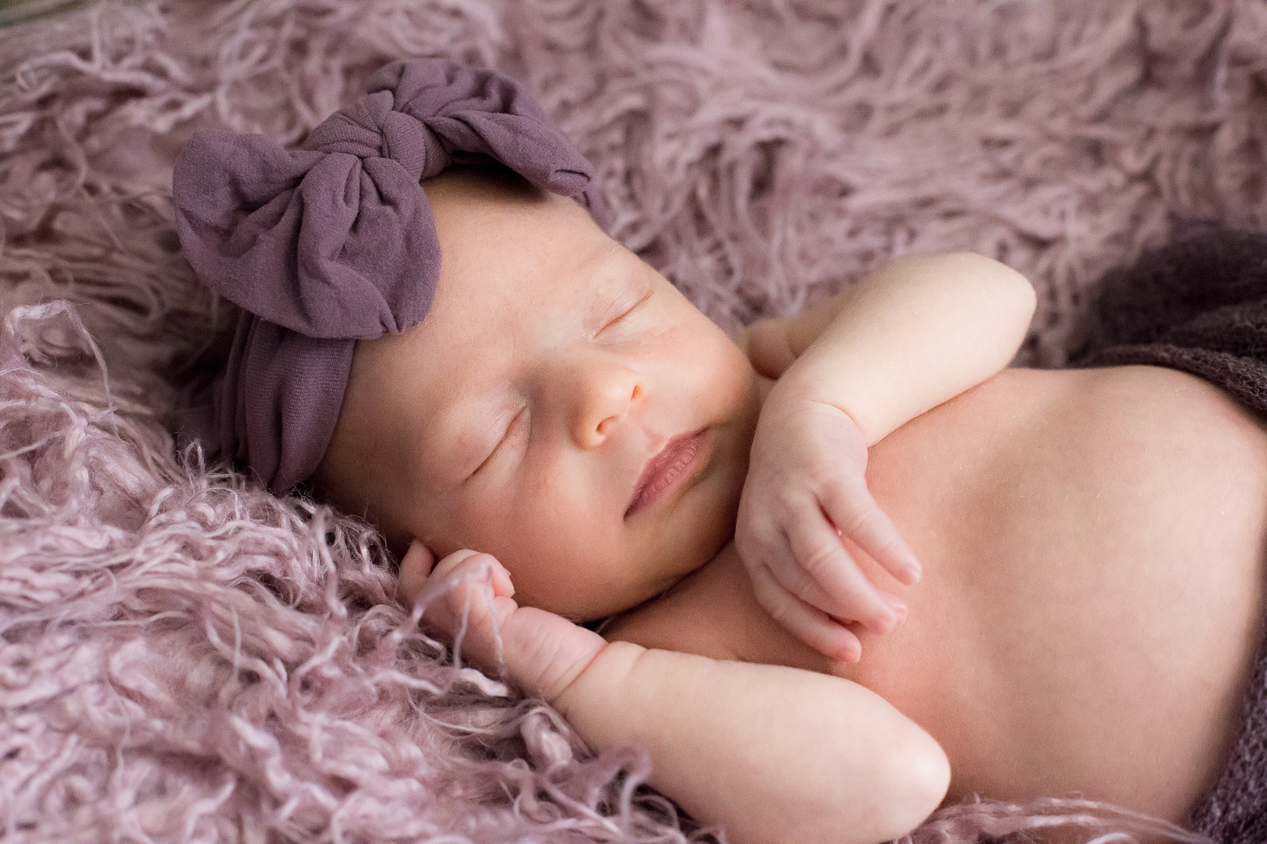 Nahaufnahme eines neugeborenen Kleinkindes mit Babymütze schlafend im Fellbettchen