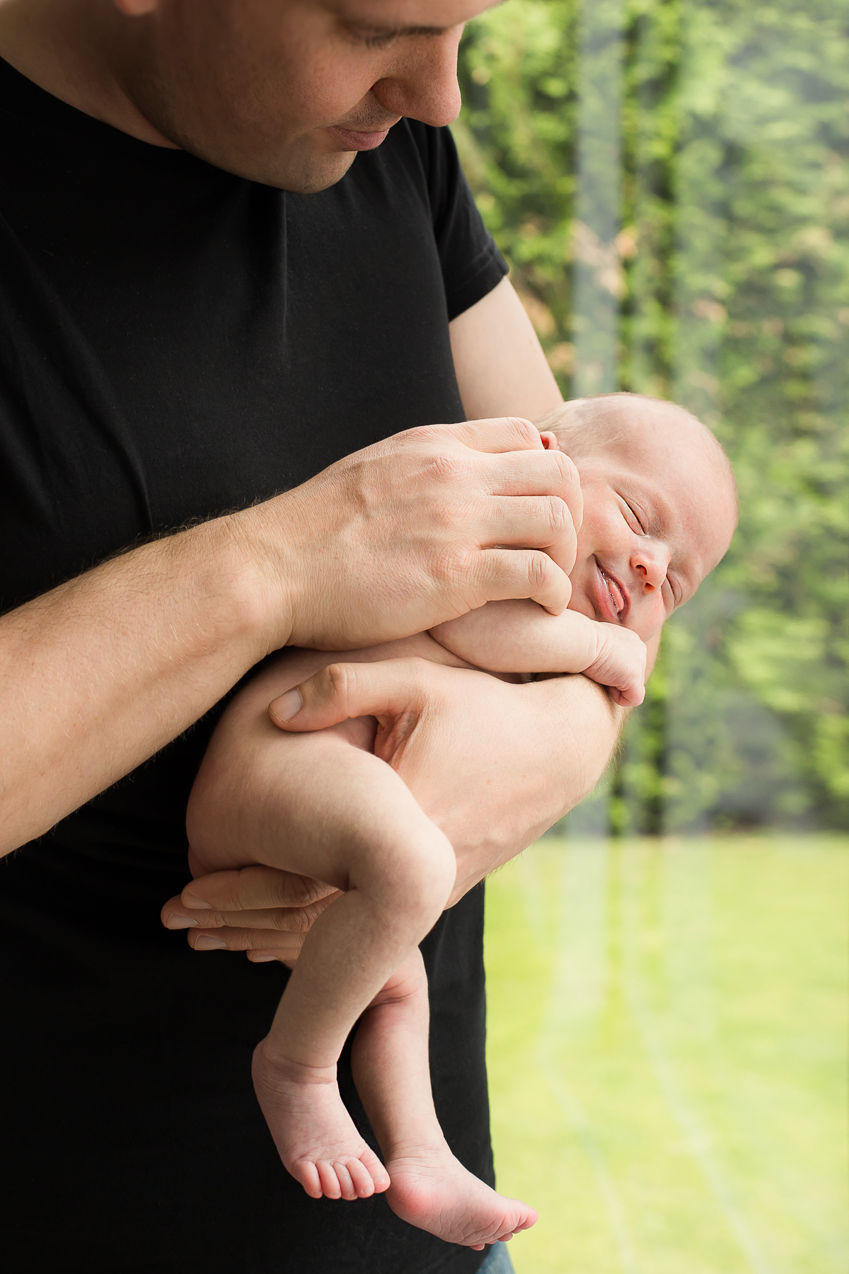 Neugeborenes unverhülltes Baby bei Papa auf dem Arm