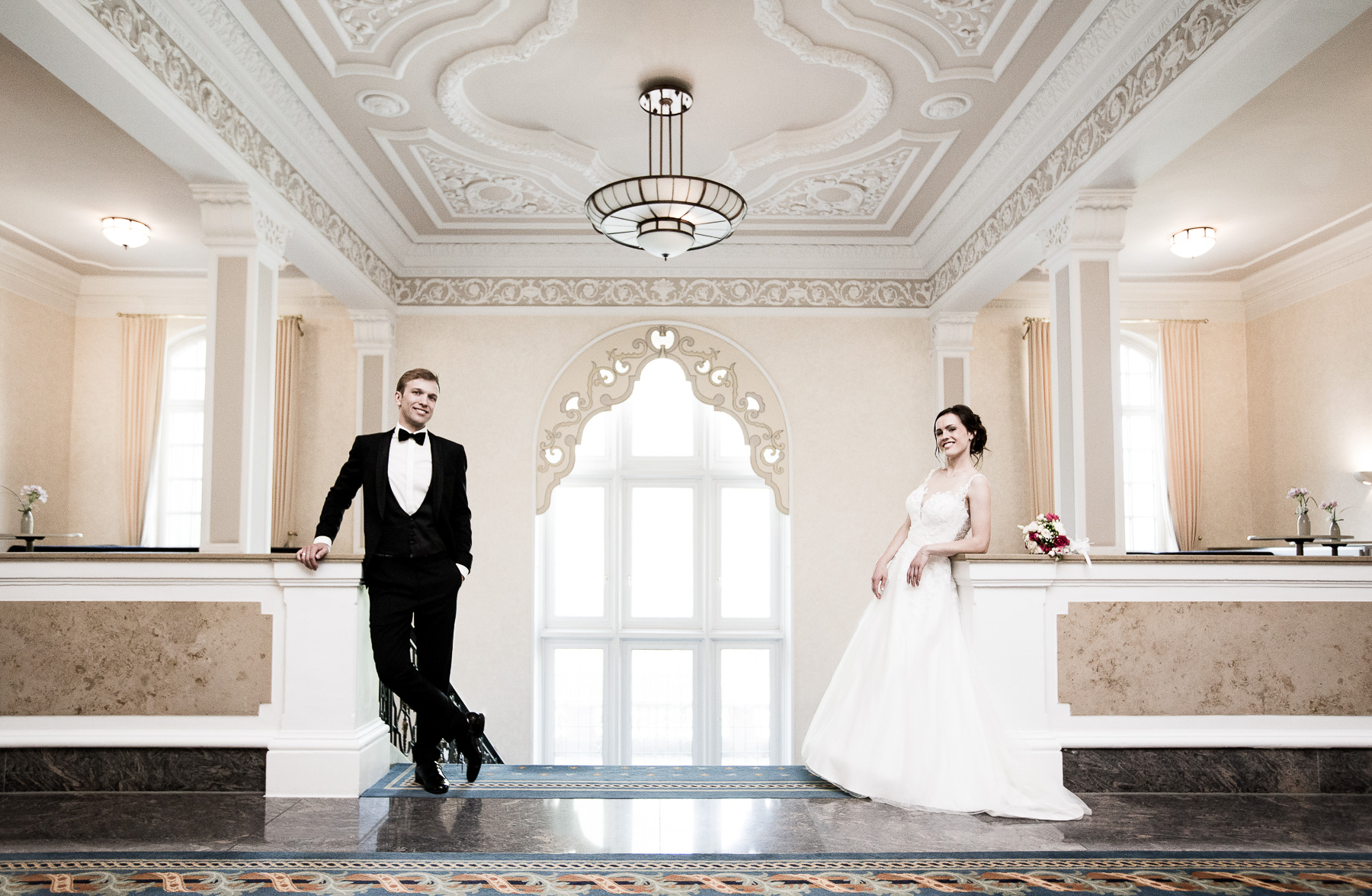 Das Brautpaar lehnt sich an die Geländer des fürstlich gestalteten BASF Gesellschaftshauses an und schaut in die Kamera.