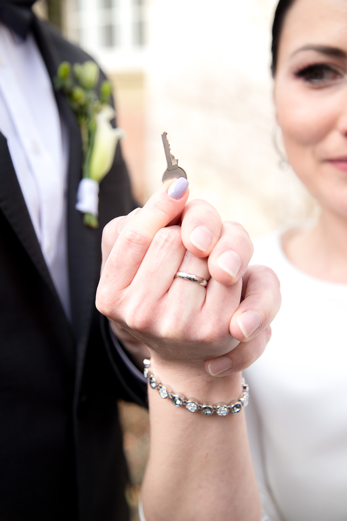 Das Brautpaar hält gemeinsam den Schlüssel ihres Liebesschlosses in ihren Händen hoch
