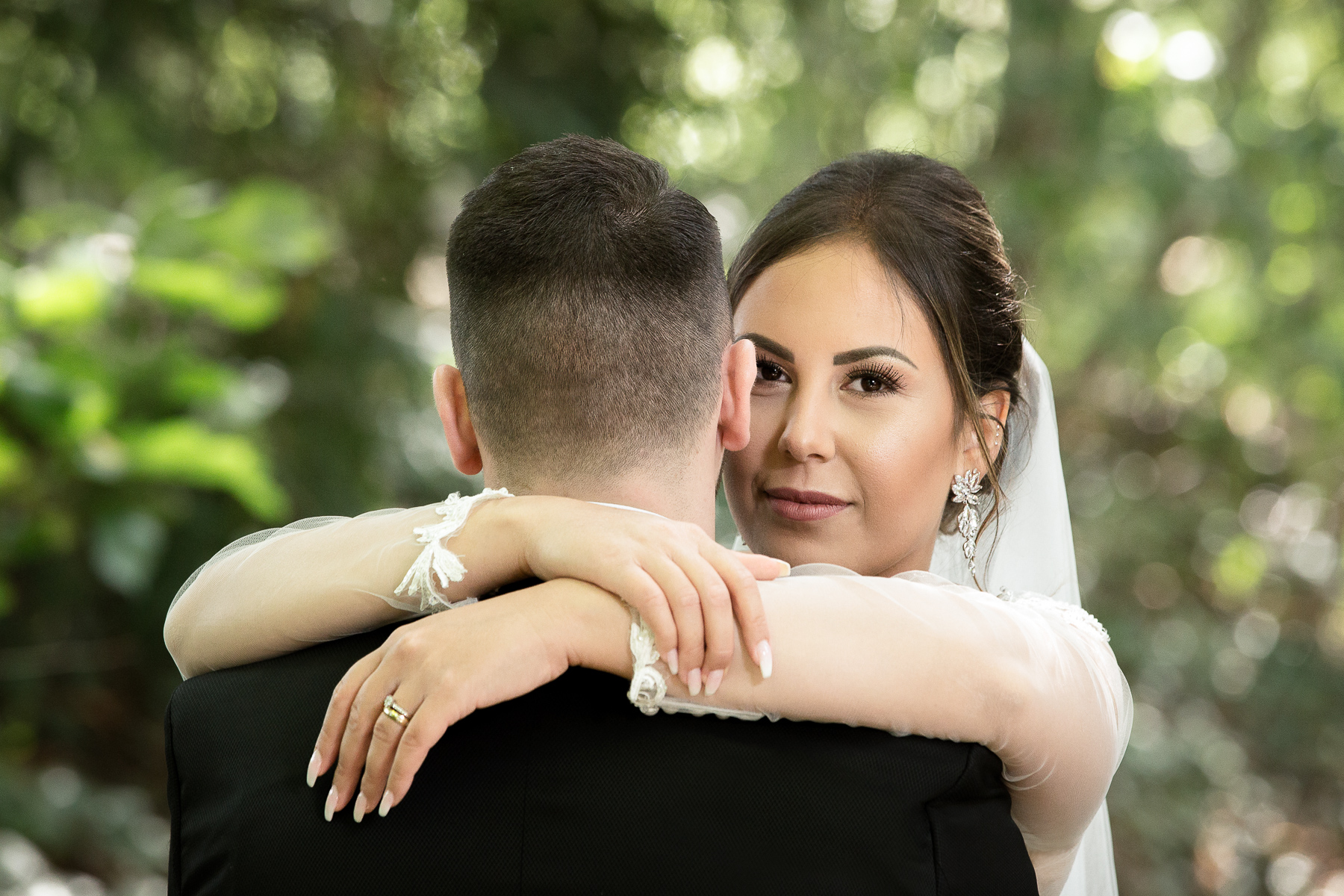 Der Bräutigam steht mit dem Rücken zur Kamera, während die Braut ihn umarmt und frontal in die Kamera schaut.