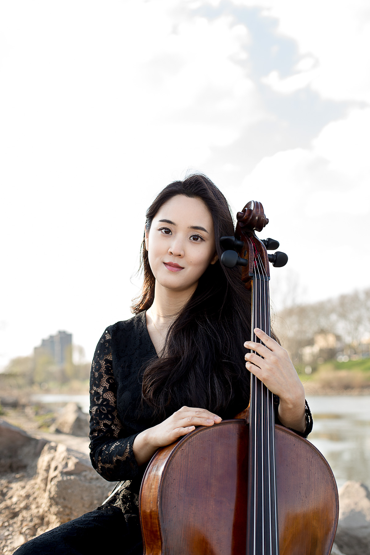 Outdoorportraitfoto einer asiatischen, jungen Singlefrau mit Cello am Neckar in Mannheim