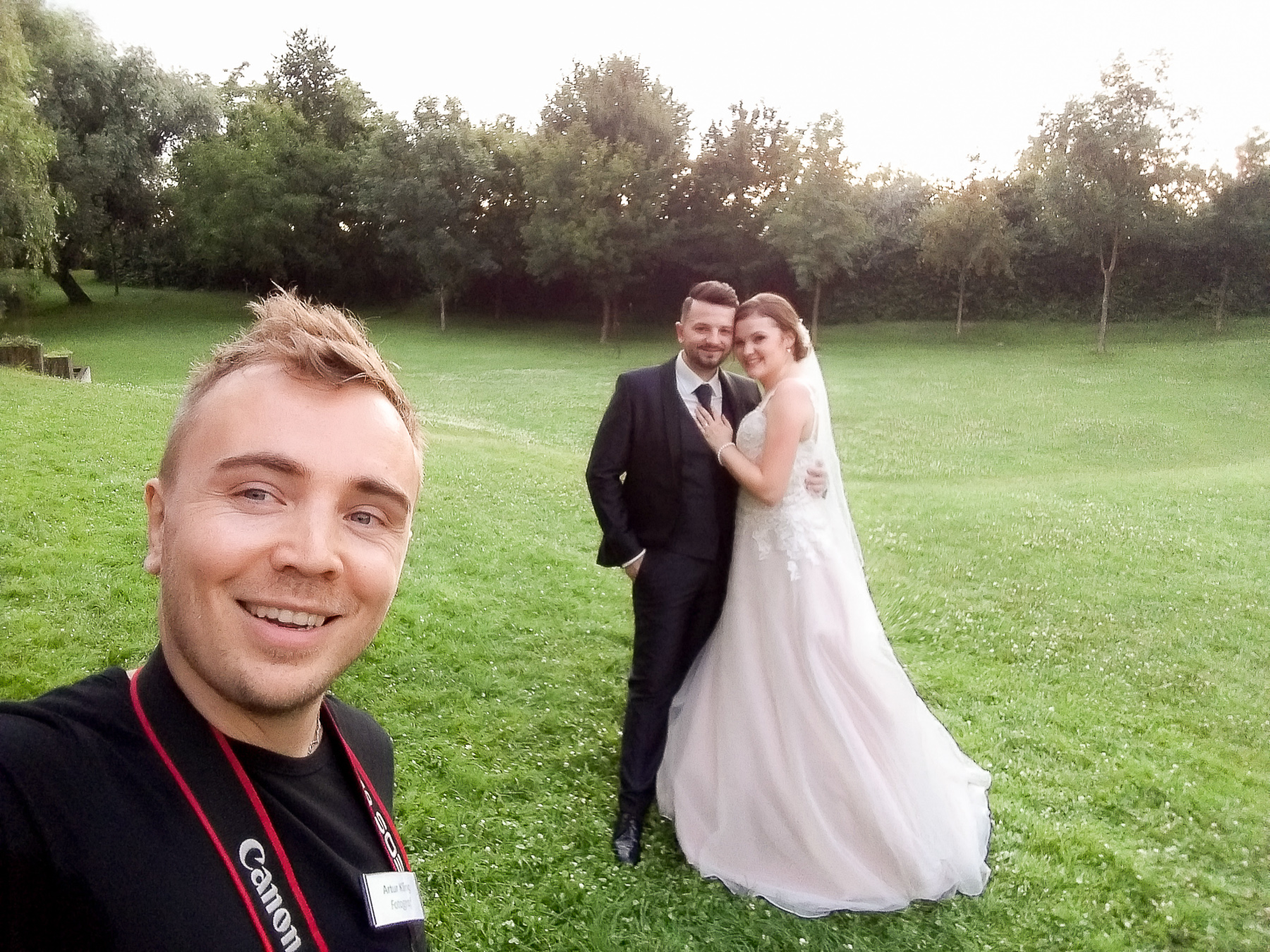 Fotograf macht Selfie mit Traupaar im Hintergrund