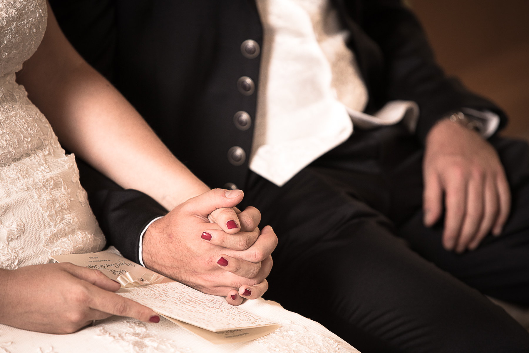 Die fest verschränkten Hände von der Braut und dem Bräutigam während einer kirchlichen Trauung.
