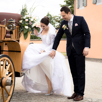 Hochzeitsreportage - Der Bräutigam hilft der Braut beim Aussteigen aus der Kutsche.