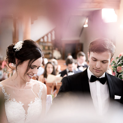 Das Brautpaar nebeneinander fotografisch umhüllt von Hochzeitsdekorationen. Sie sehen nach unten und lächeln.
