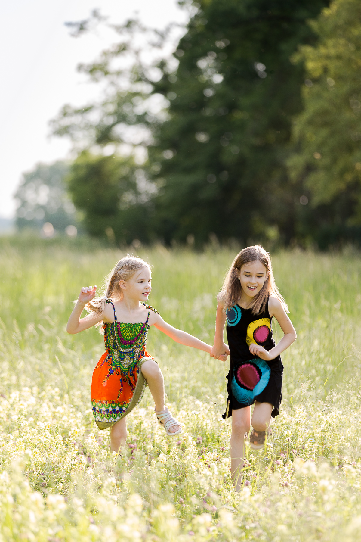 Zwei junge Geschwister rennen im Feld und freuen sich