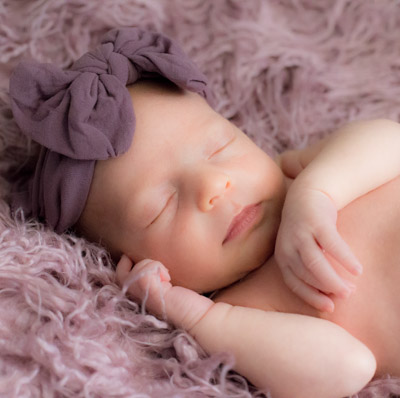 Babyfotograf für Neugeborenenfotos. Ein süßes Baby im kuschligen Fell.