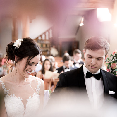 Hochzeitsreportage - Ein Brautpaar schaut während einer kirchlichen Trauung hinunter.